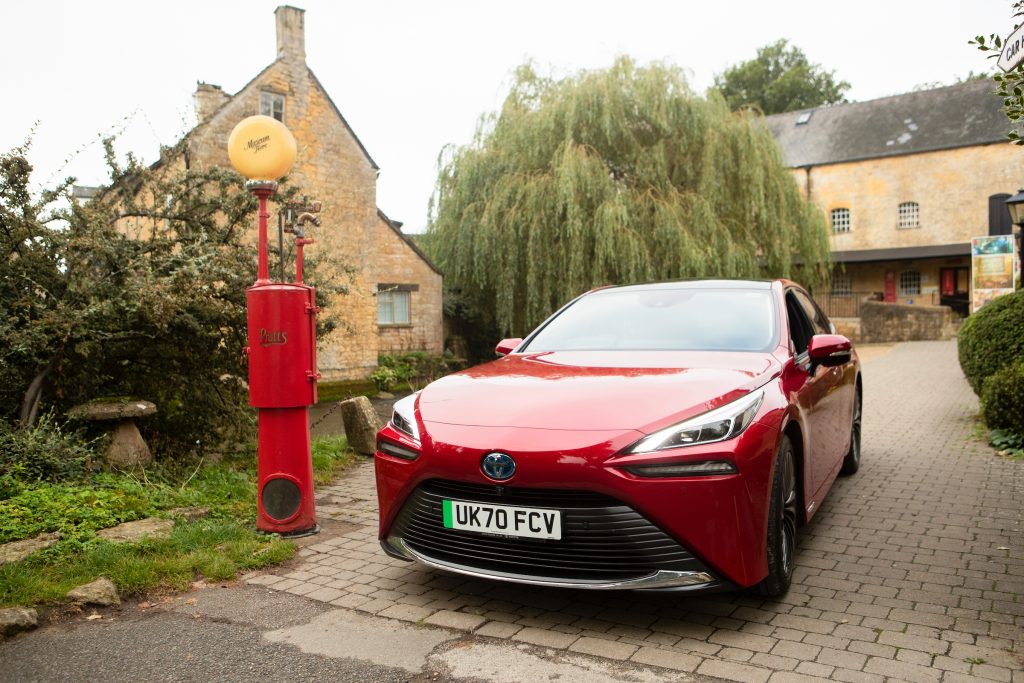 The real new generation Toyota Mirai parks beside a vintage petrol pump outside the Motor Museum in Bourton-on-the-Water.