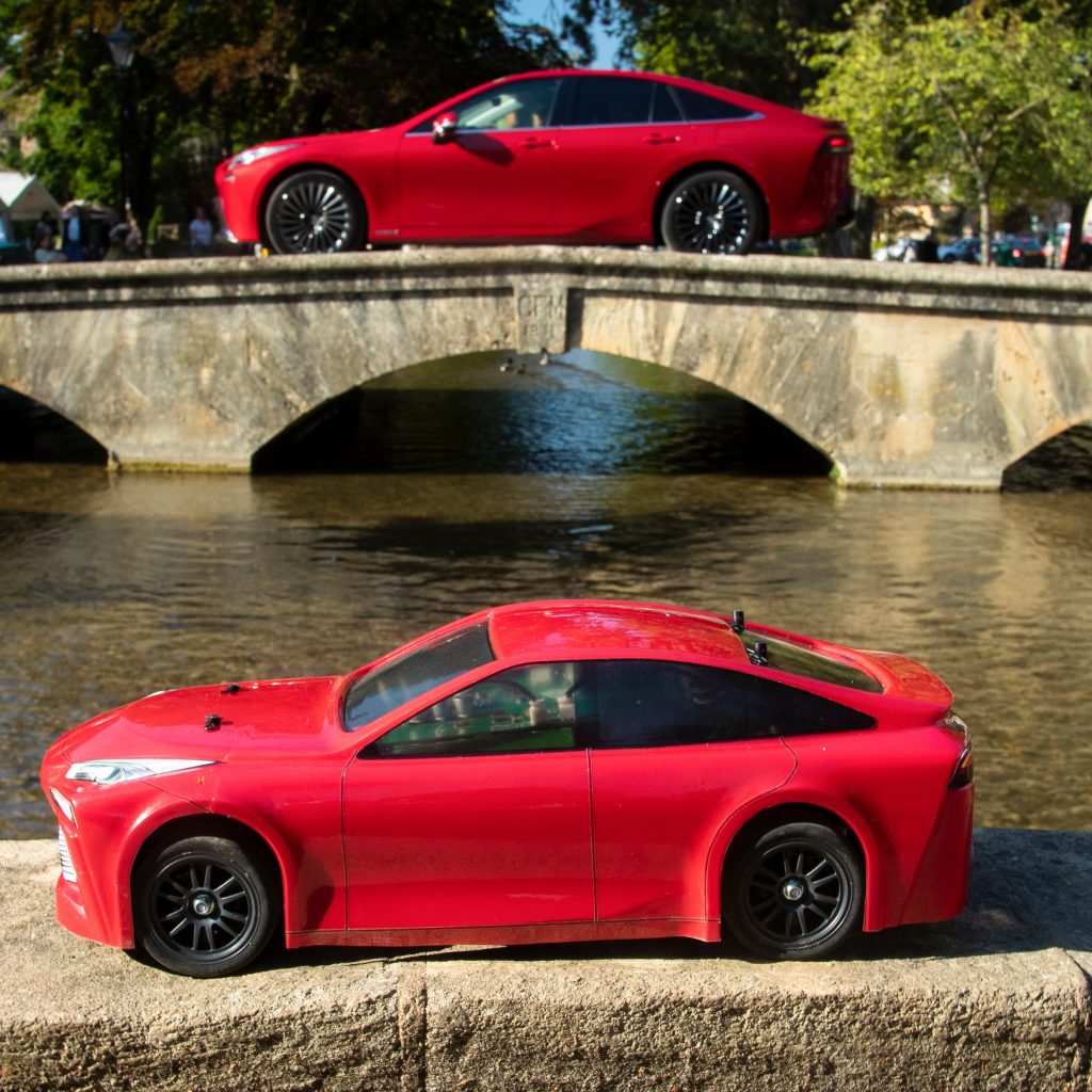 Both little and large Mirai hydrogen-fuelled cars, only emitting water from their exhausts, cross the river in Bourton-on-the-Water.