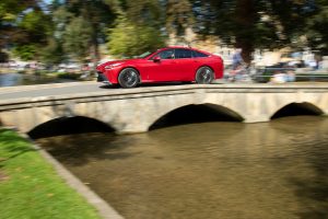 The full-size Mirai hydrogen car crosses a bridge in Bourton-on-the-Water.