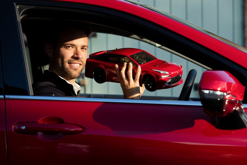 Alistair Brebner of Tamiya UK with his company’s Tamiya model Mirai RC car, sitting inside a full-sized Toyota Mirai.